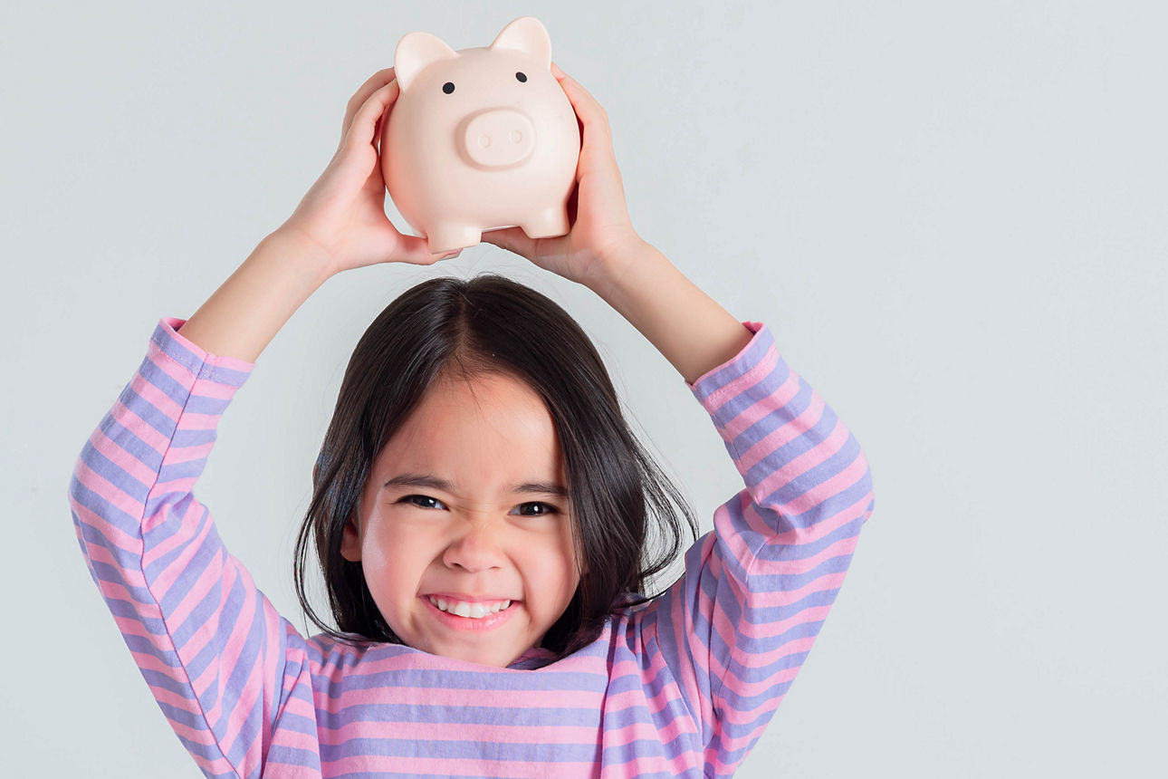 Kleines Mädchen spart Geld in einem Sparschwein