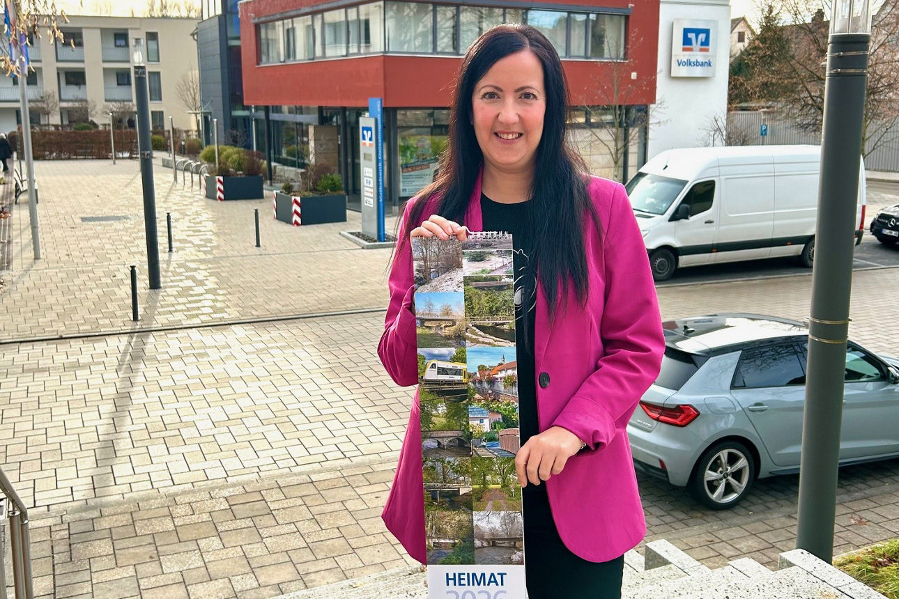 Mitarbeiterin Gabriele Maier mit Heimatkalender 2026 vor Bankgebäude in Deißlingen