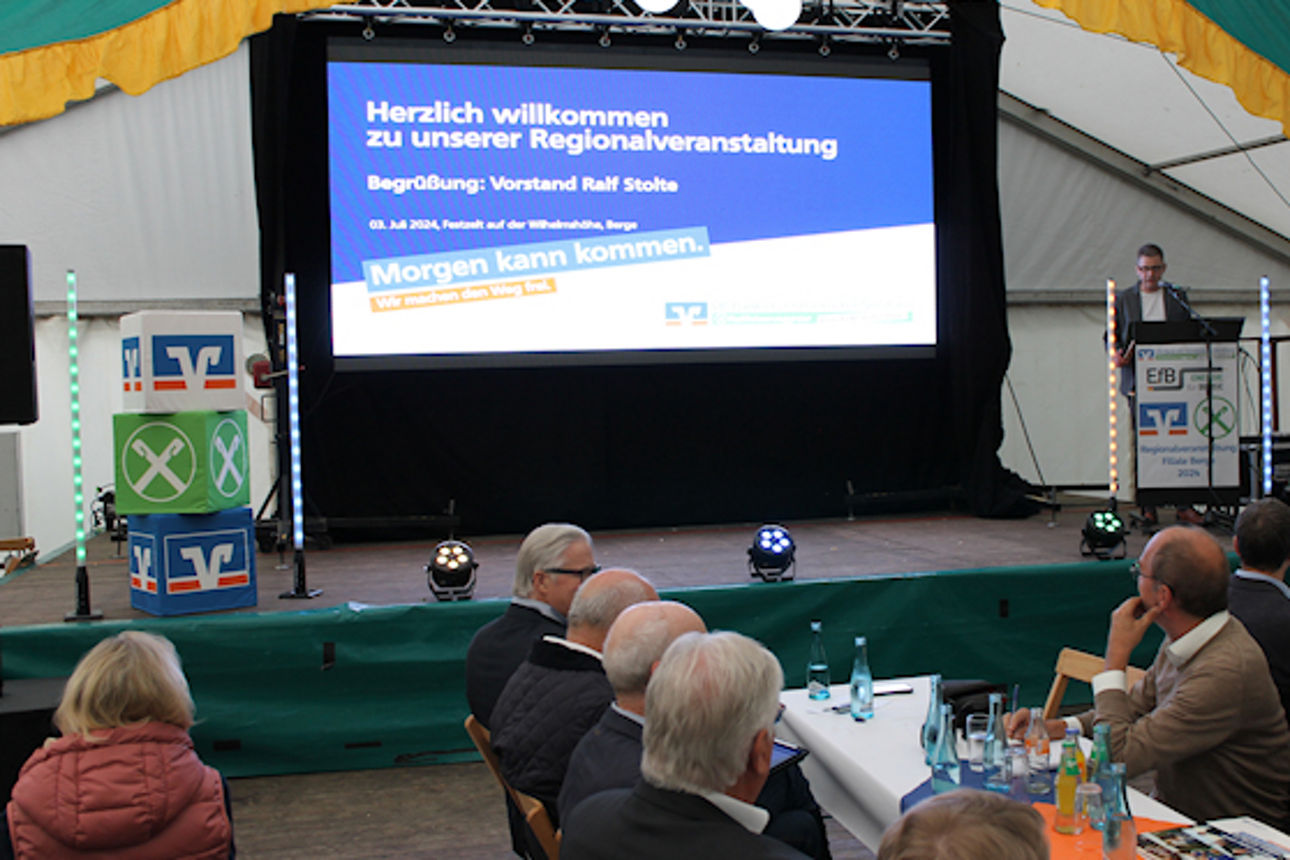 Eine bunt gemischte Gruppe von Menschen versammelte sich um einen Tisch in einem Zelt, unterhielt sich und tauschte Ideen aus