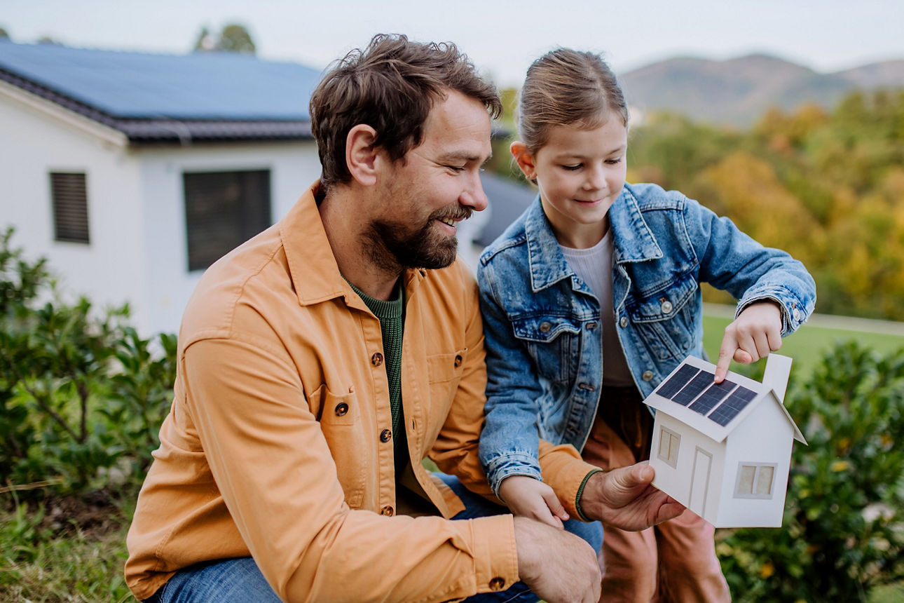 Mann zeigt Tochter anhand eines Modells eine Photovoltaikanlage