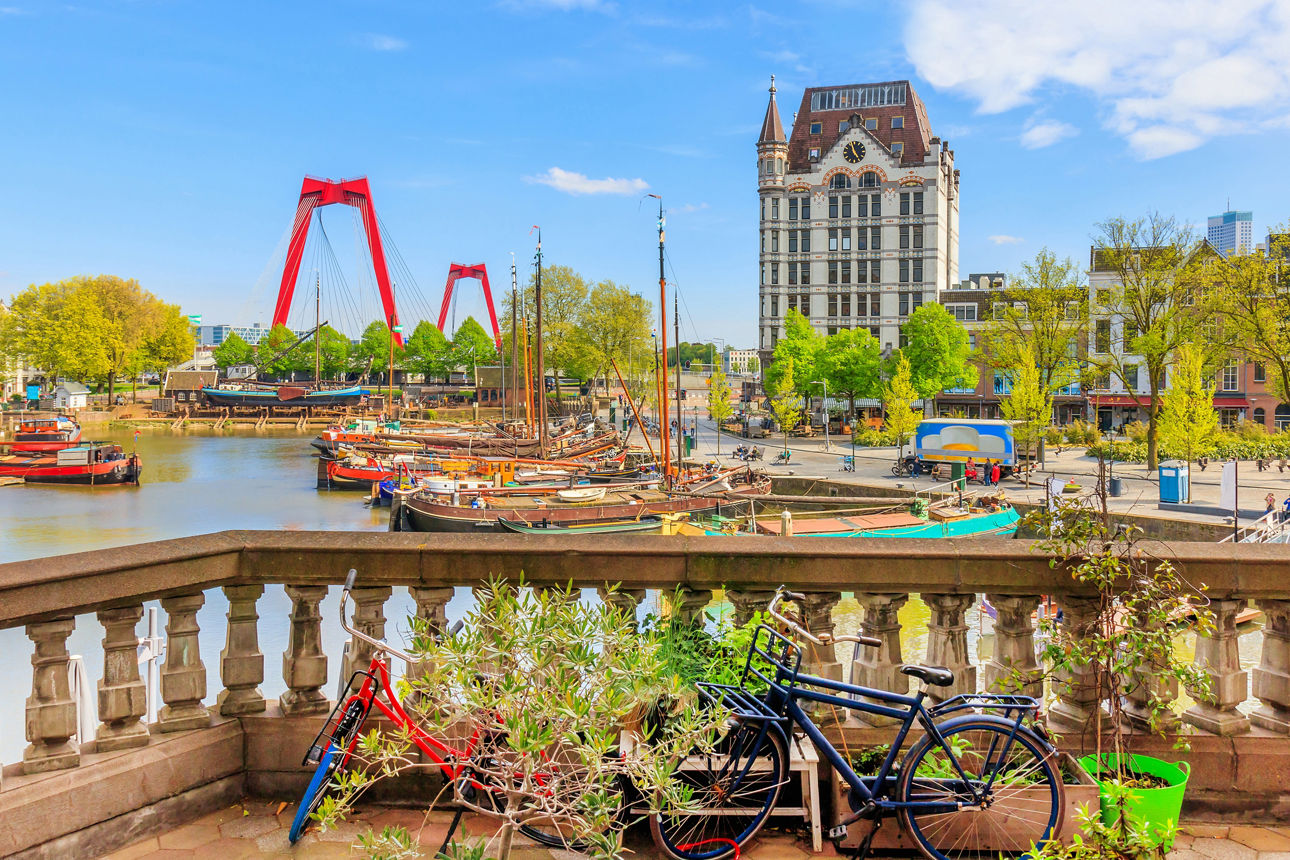 Amsterdam. Im Vordergrund steinerne Balustrade mt zwei Fahrrädern. Im Hintergrund traditionelle Schiffe im Hafenbecken.