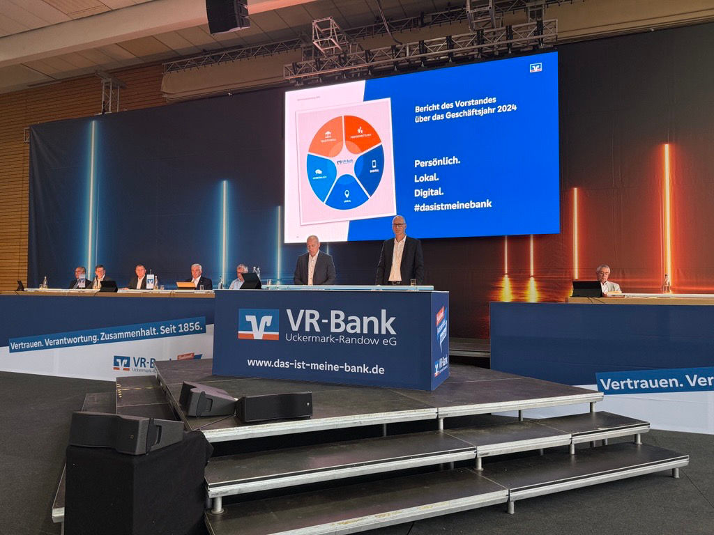 die 2 Vorstände stehen hinterm Podium vor der Generalversammlung