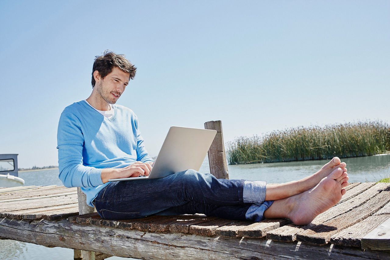 Mann mit Tablett auf einem Steg am Wasser
