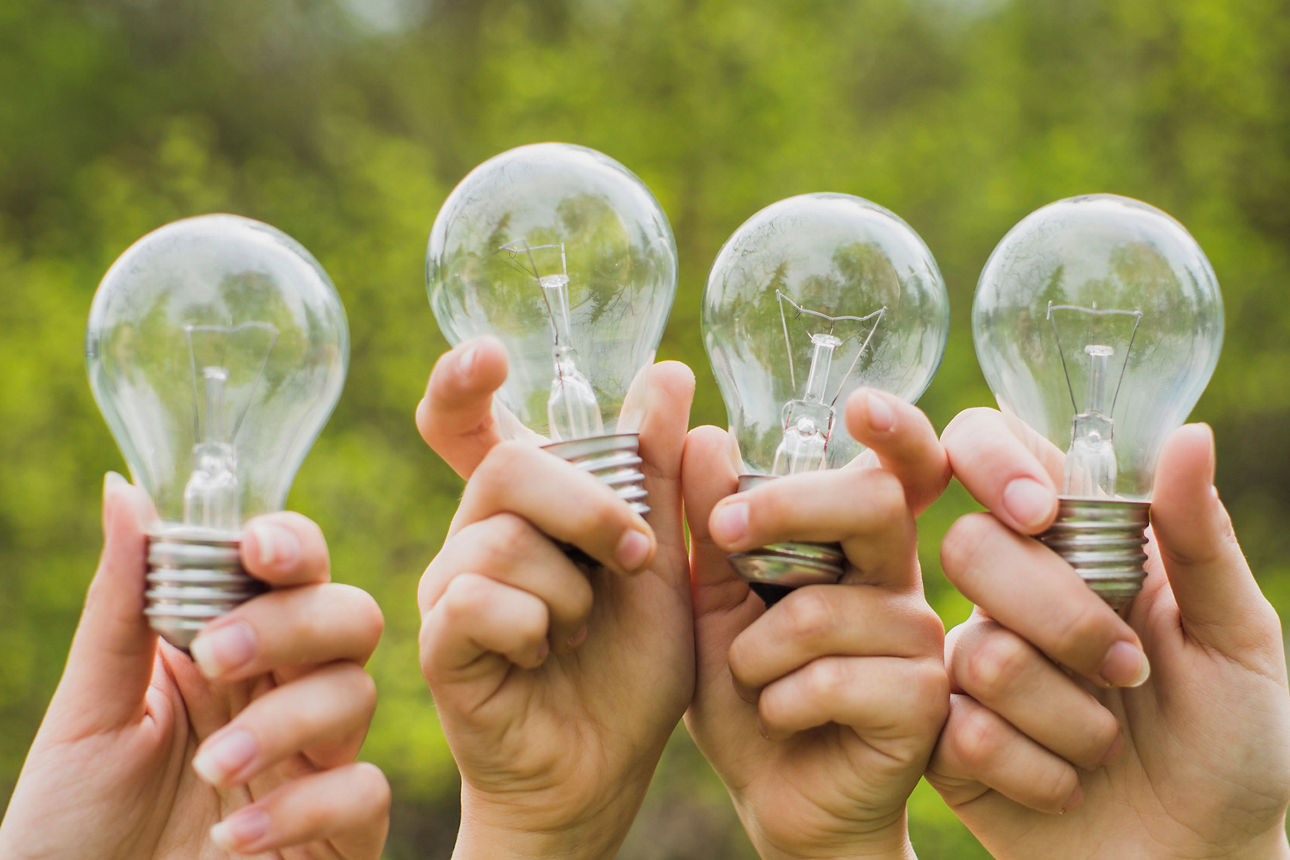 Vier Hände mit jeweils einer Glüchbirne