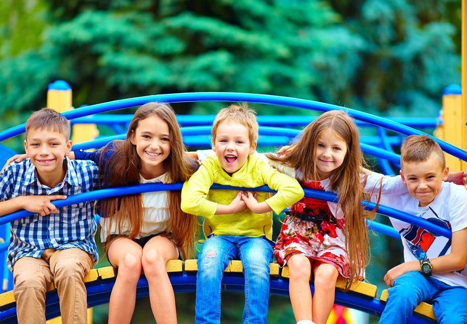 Fünf Kinder sitzen auf einem Spielgerät und lachen