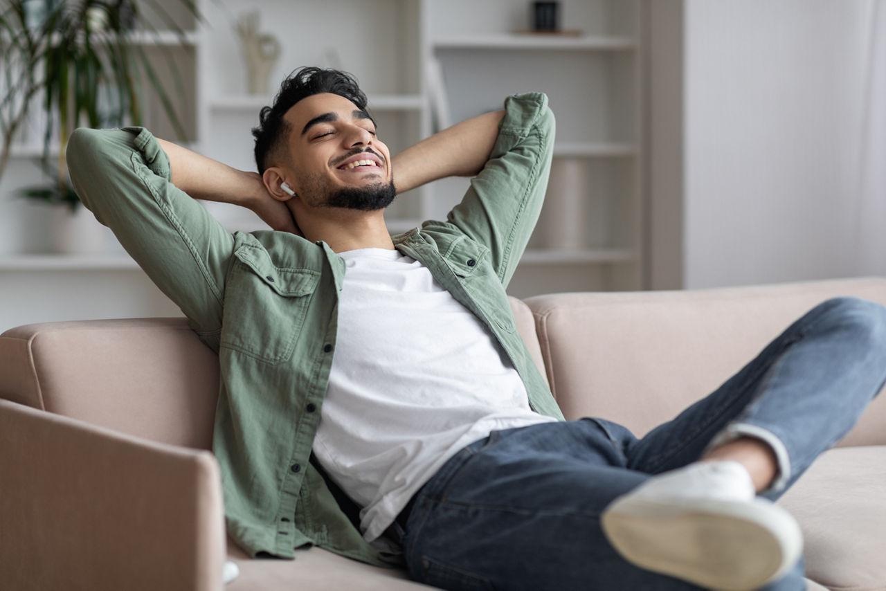Ein Mann lehnt sich auf einem Sofa zurück und hört Musik