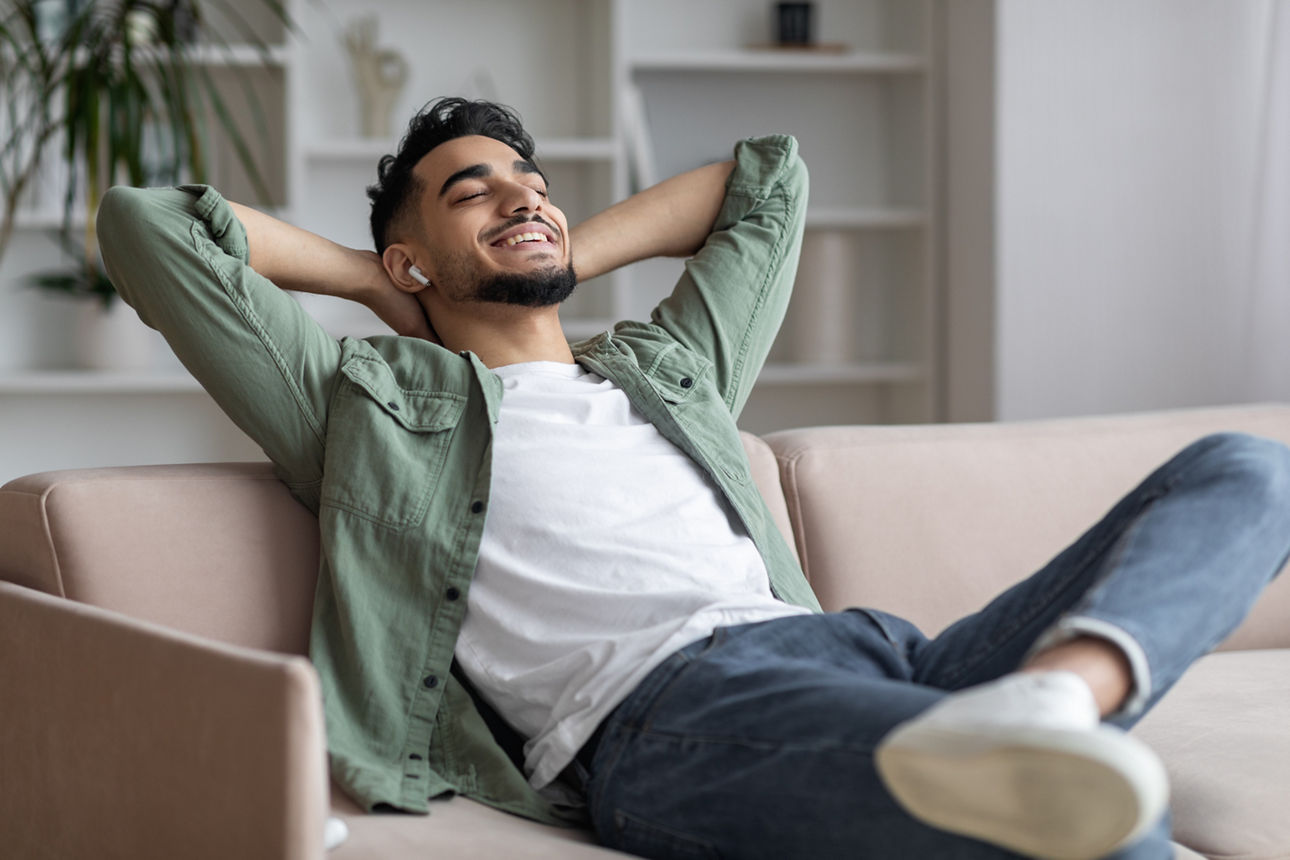 Ein Mann lehnt sich auf einem Sofa zurück und hört Musik