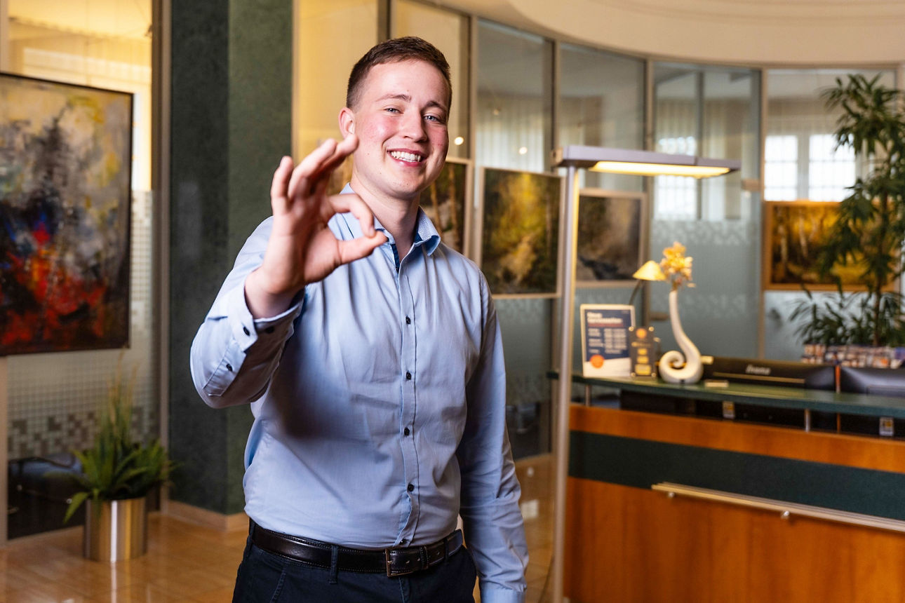 Junger Mann zeigt mit Dauemen und Zeigefinger, dass er etwas sehr gut findet.