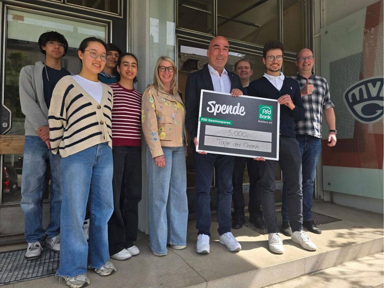 Mehrere Personen halten einen Scheck