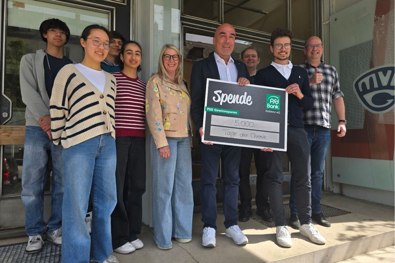 Eine Gruppe Personen posiert mit einem Spendenscheck