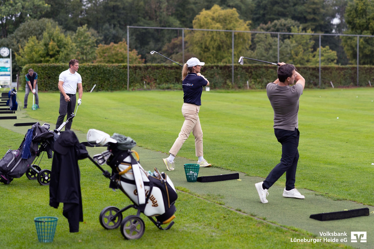 vier Golfer auf der Driving Range beim Abschlag