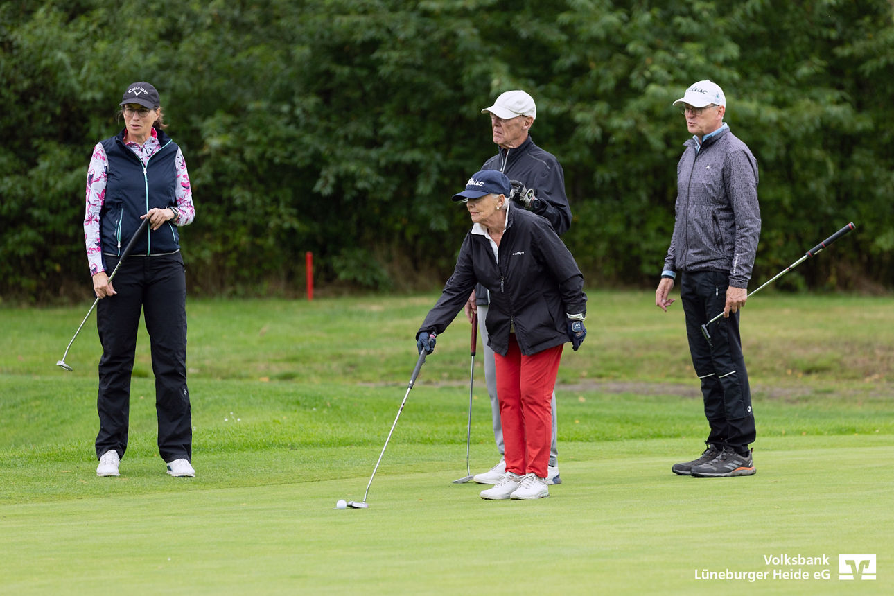Ein Flight auf dem Golfplatz beim Abschlag, drei Männer und eine Frau in roter Hose