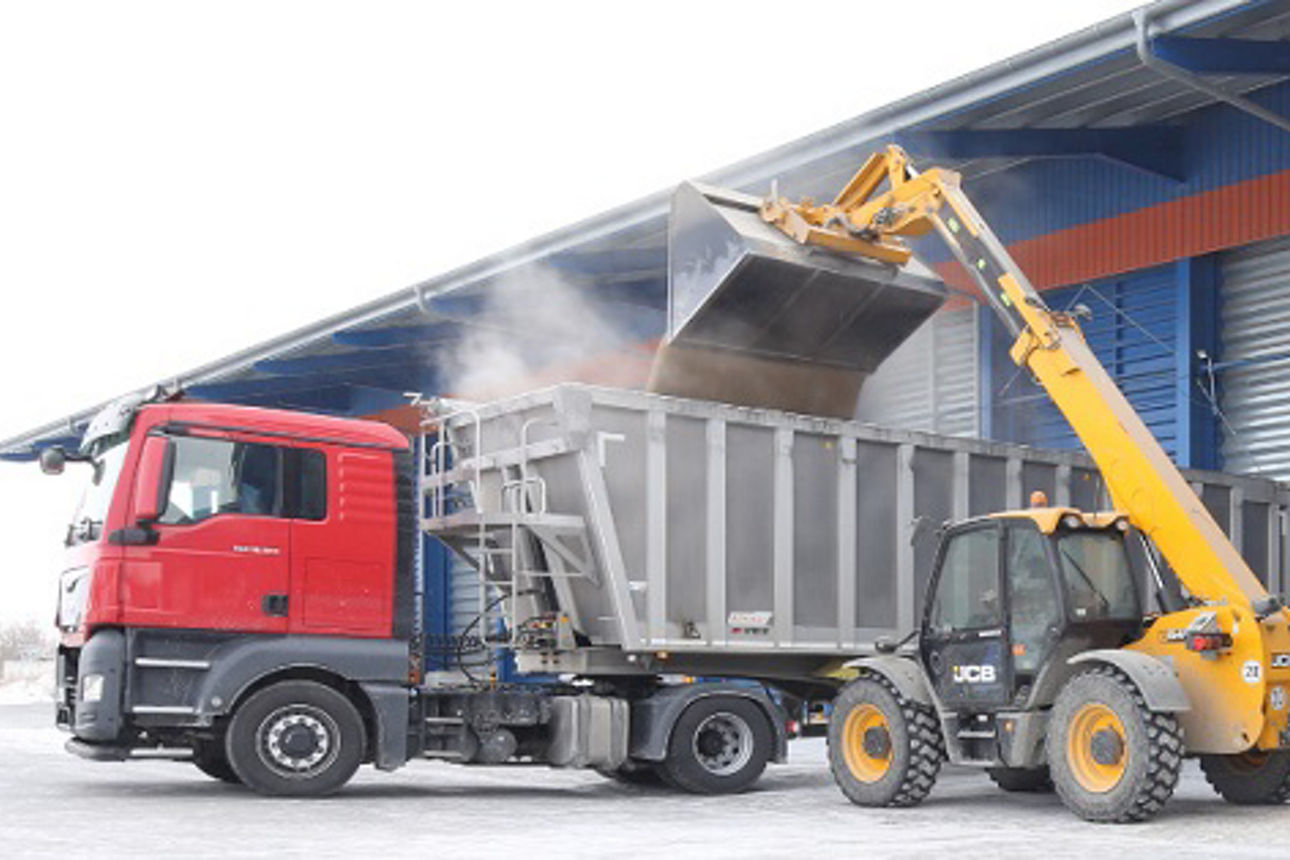 Ein Lastwagen und ein Kipplaster sind vor einem Gebäude geparkt