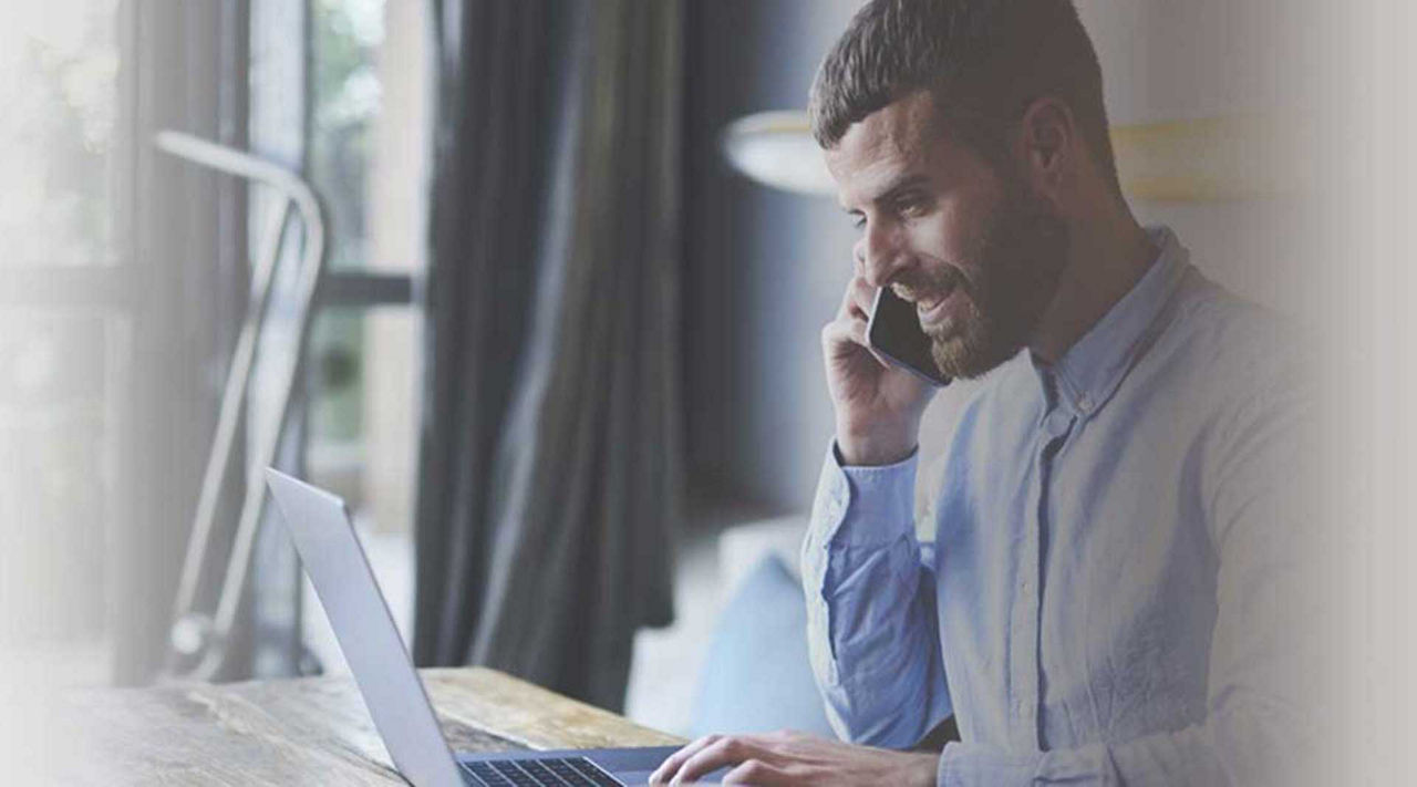 Leasing Mann sitzt am Laptop und telefoniert