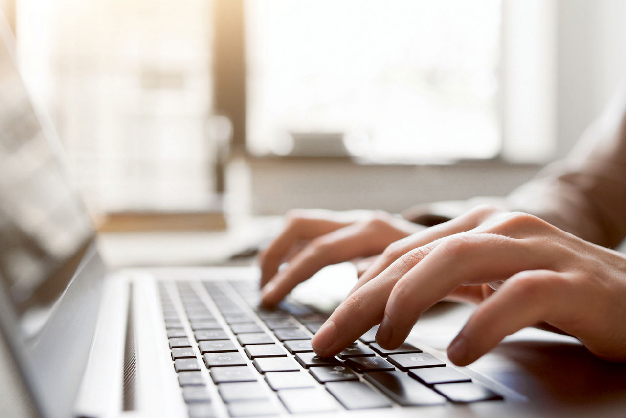Zwei Hände, die auf der Tastatur eines Laptops tippen