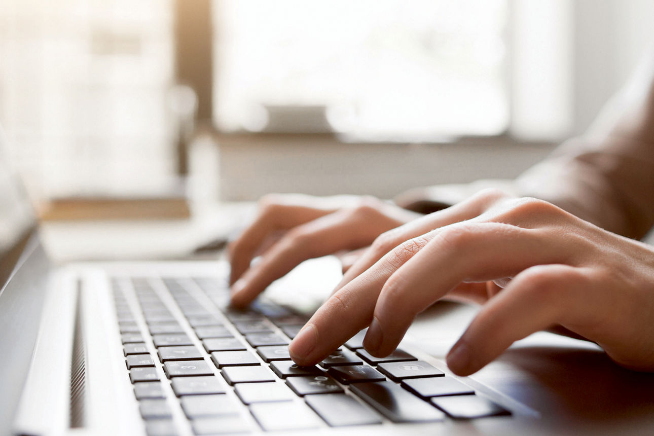 Zwei Hände, die auf der Tastatur eines Laptops tippen