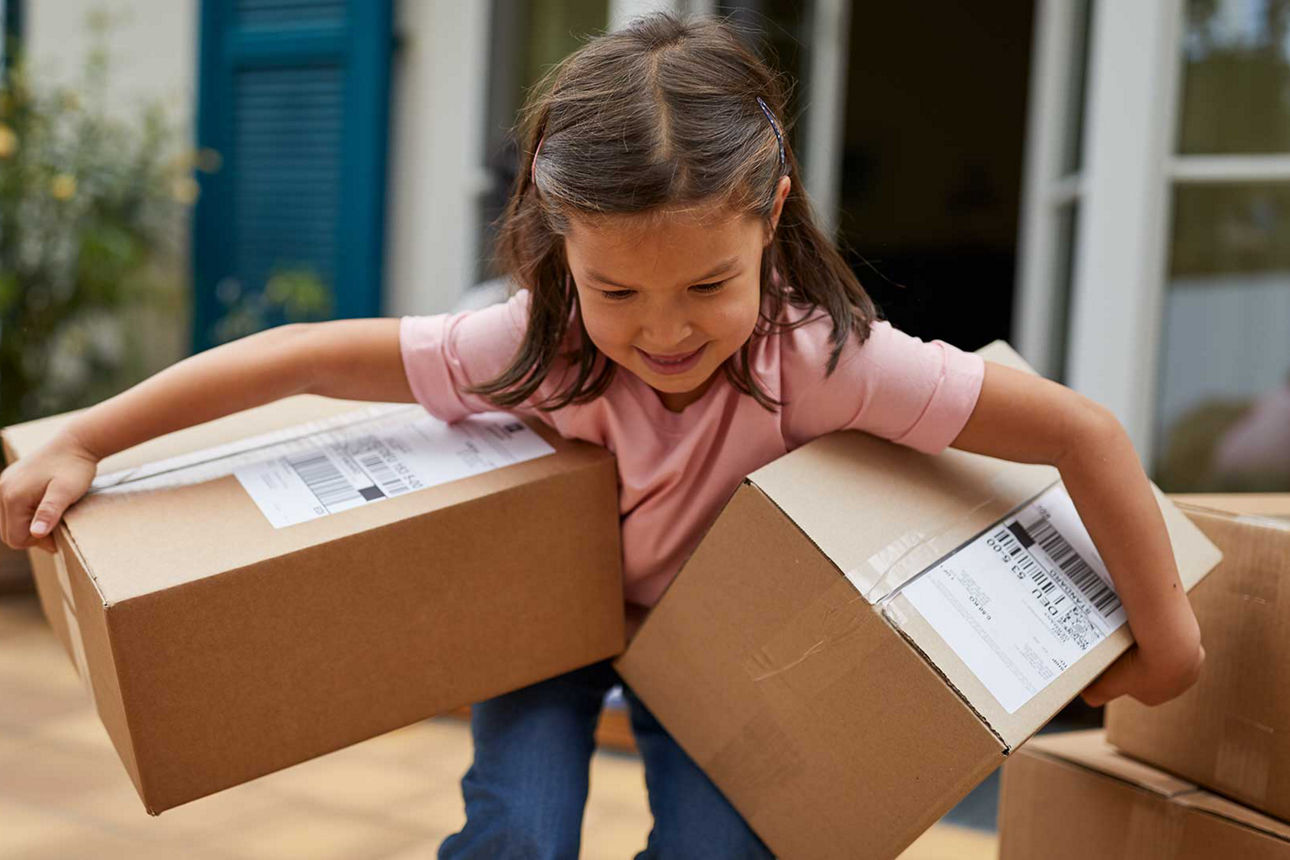 Kleines Mädchen schleppt zwei große Kartons