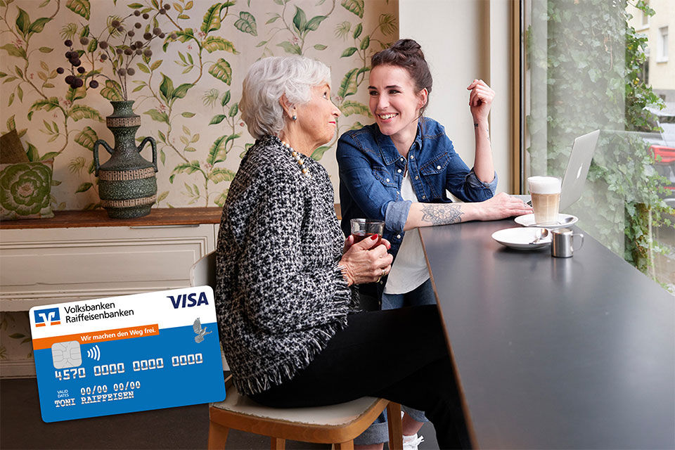 Eine ältere Frau im Gespräch mit einer jungen Frau in einem Cafè links im Bild eine Visa ClassicCard