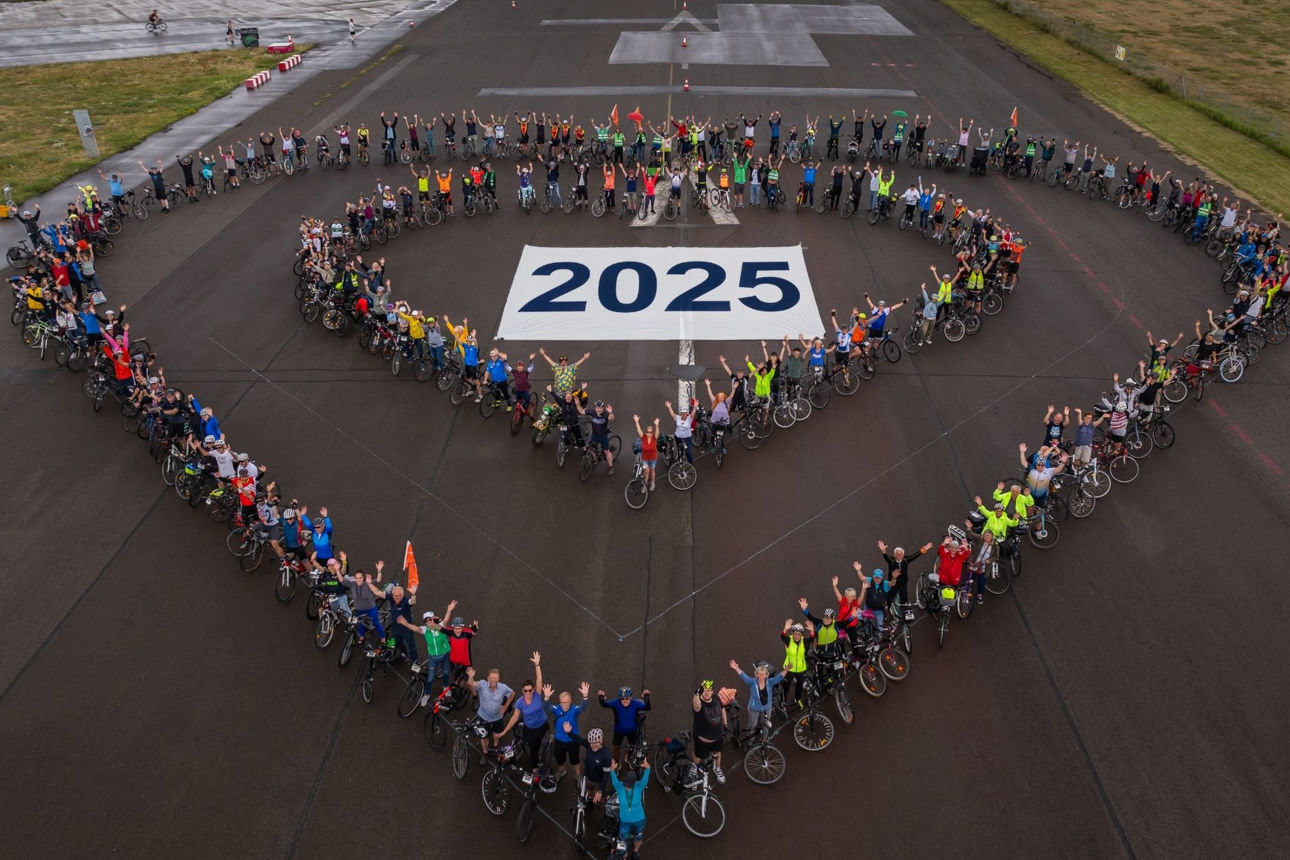 Teilnehmende der Herzfahrt 2025 stellen sich mit ihren Fahrrädern in Form eines Herzens auf