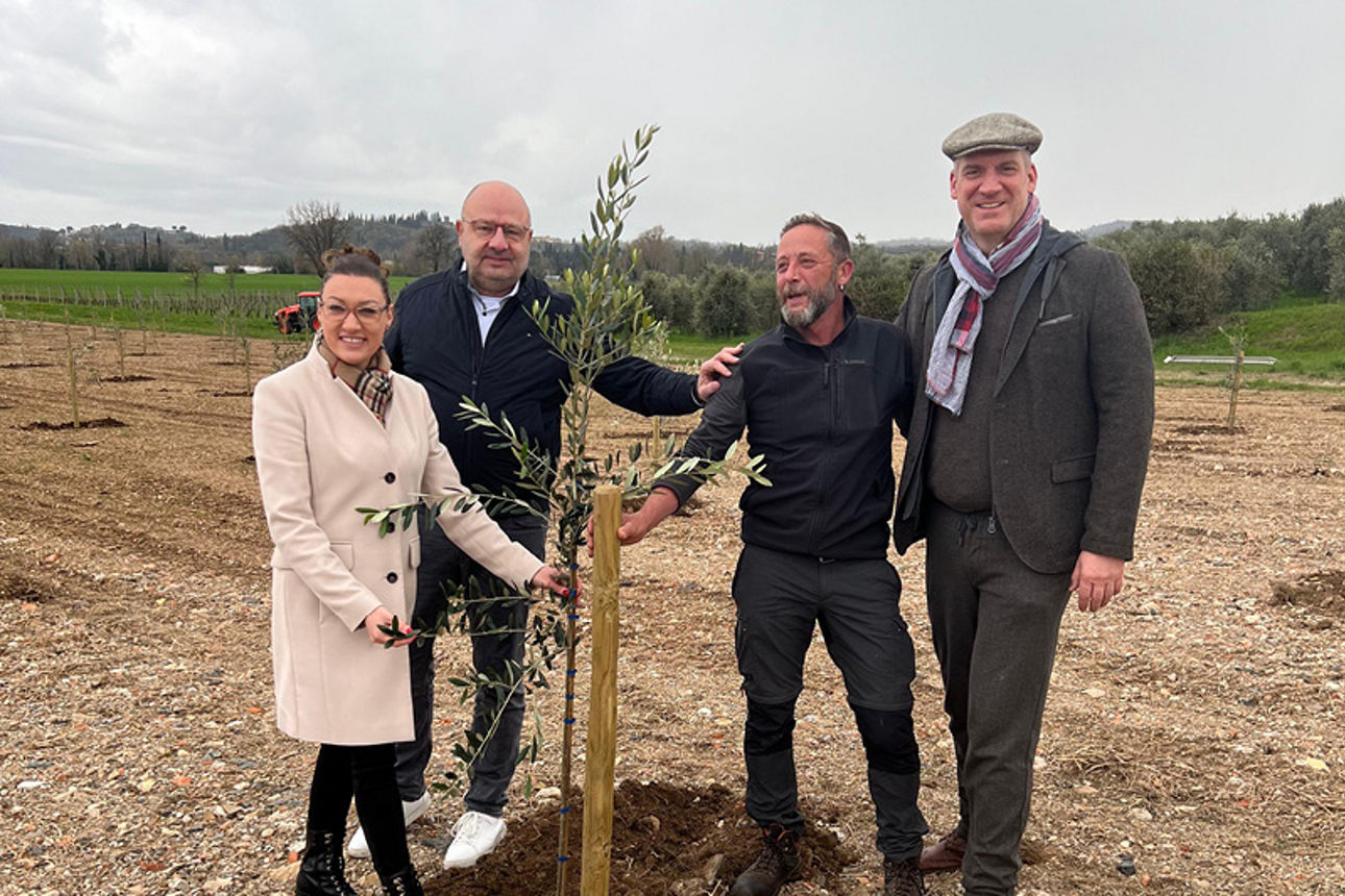 Gruppe von Menschen steht um frisch gepflanzten Baum