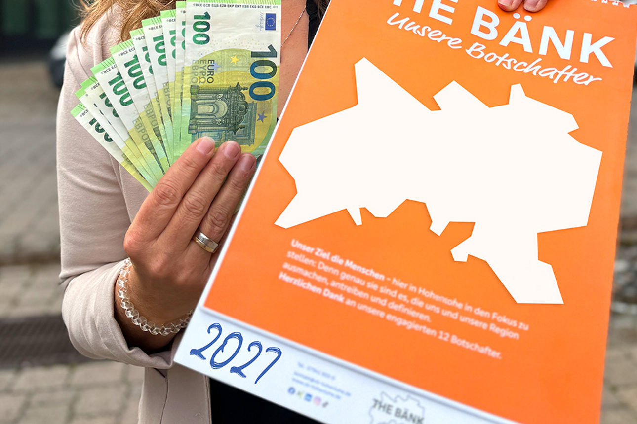 Kalender 2027 wird mit Geld in die Kamera gehalten