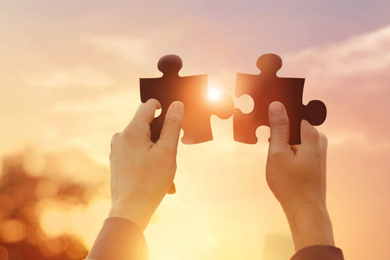 Zwei Puzzelteile werden in die Sonne gehalten