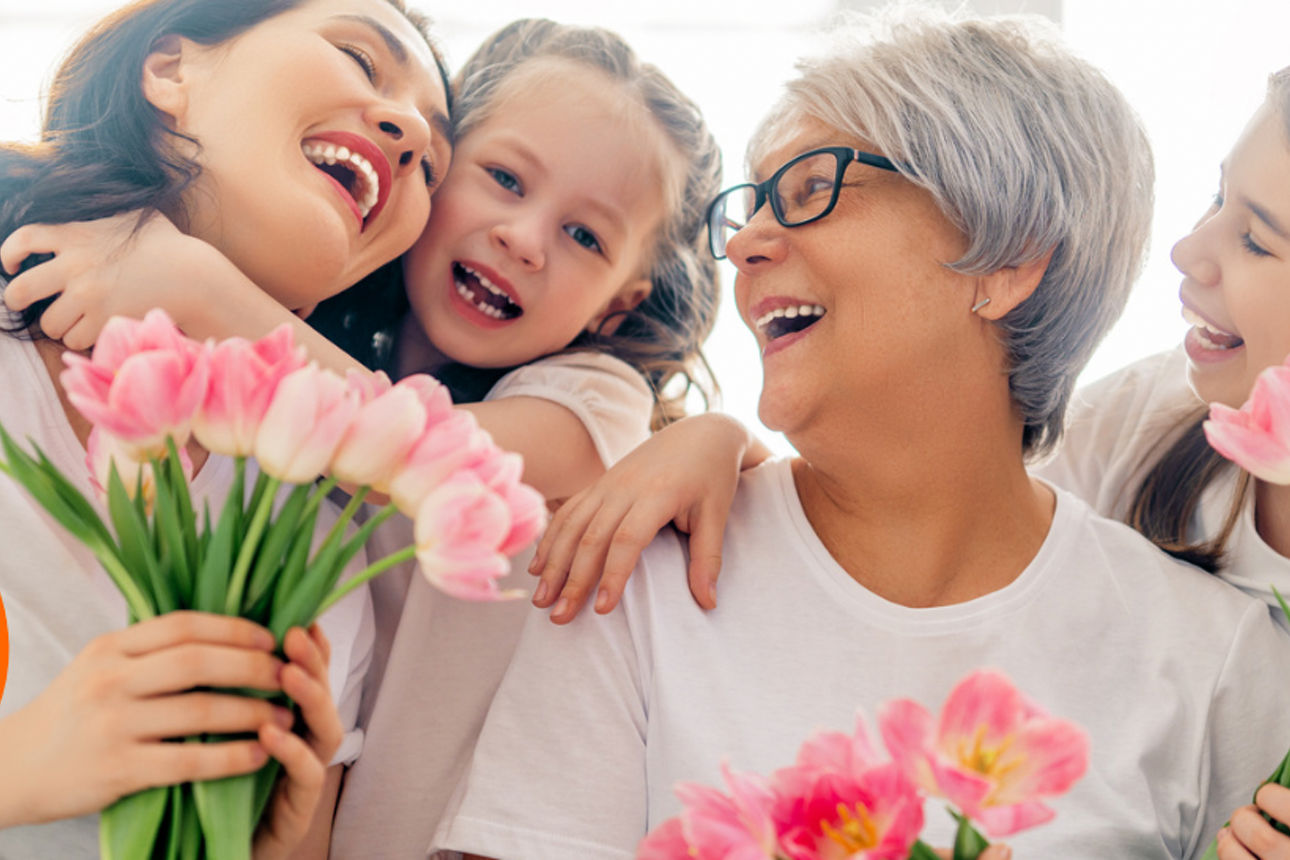 Mehrere Personen unterschiedlichen Alters stehen eng beieinander, halten rosafarbene Tulpen in den Händen.