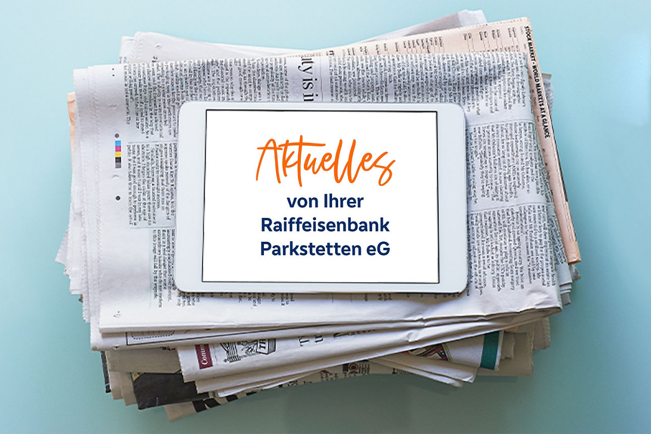 Ein Stapel Zeitungen mit Tablett mit der Aufschrift "Aktuelles von Ihrer Raiffeisenbank Parkstetten eG"