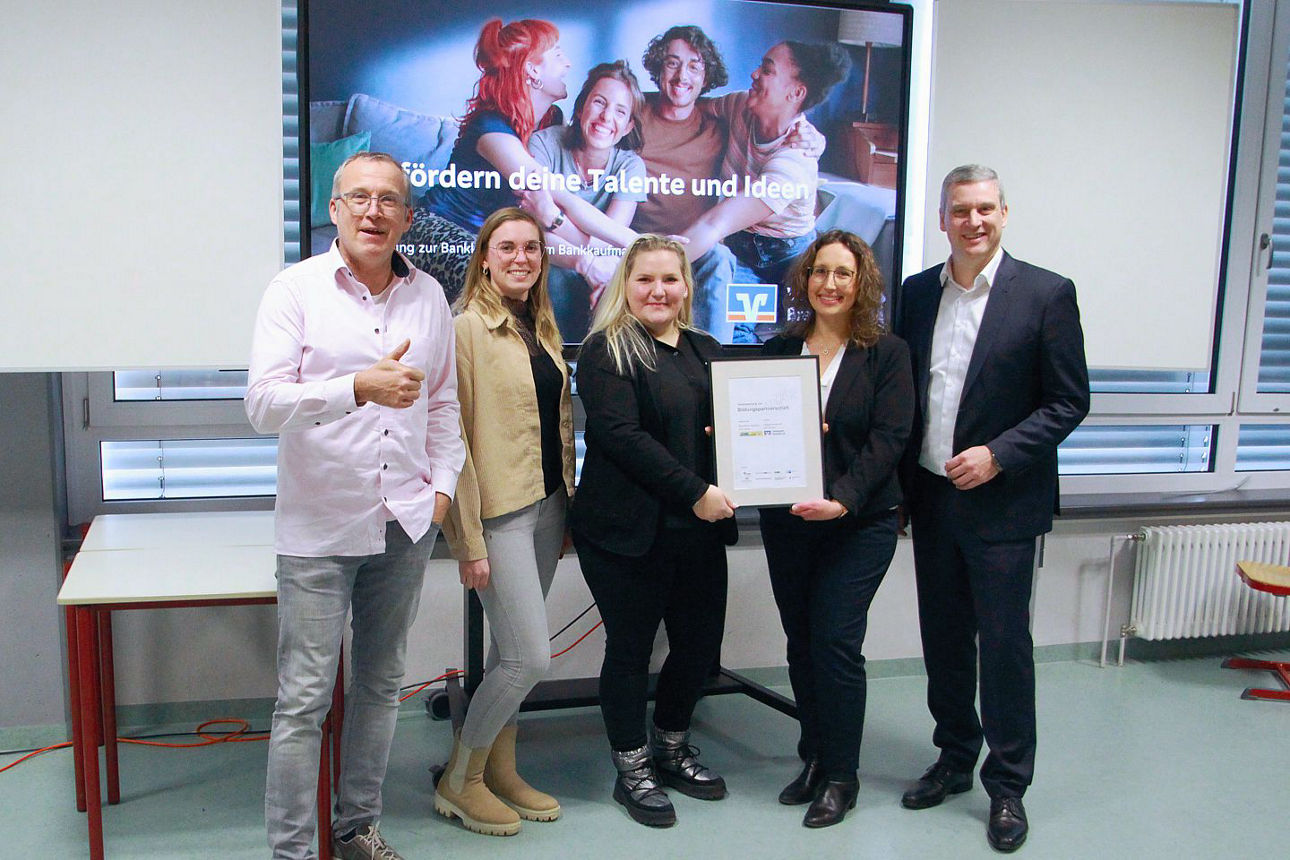 Fünf Personen stehen im Halbkreis, eine Urkunde wird in der Mitte gehalten.