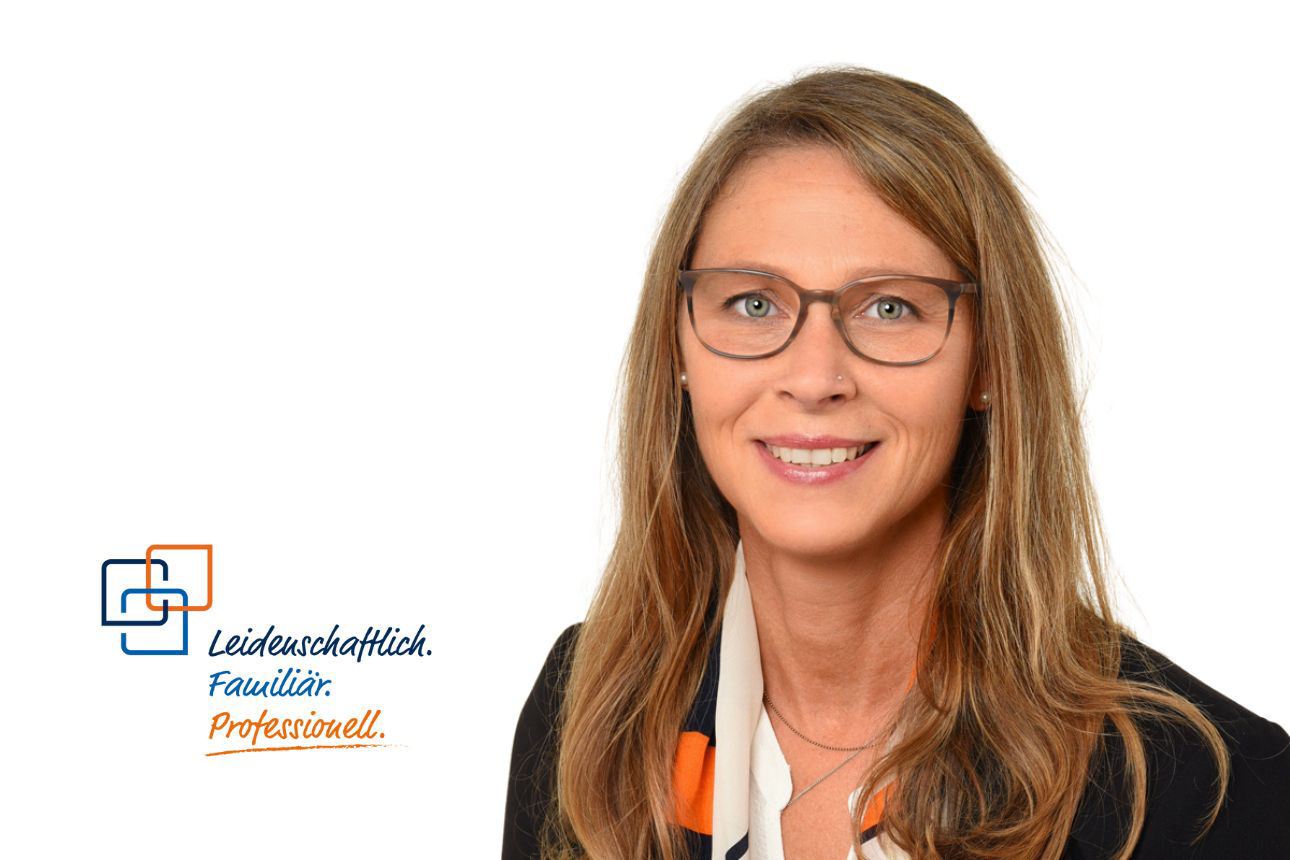 Porträt von Birgit Blöchl, einer lächelnden Frau mit langen blondbraunen Haaren, Brille und einem gemusterten Tuch. Daneben das Firmenlogo und der Slogan "Leidenschaftlich. Familiär. Professionell."