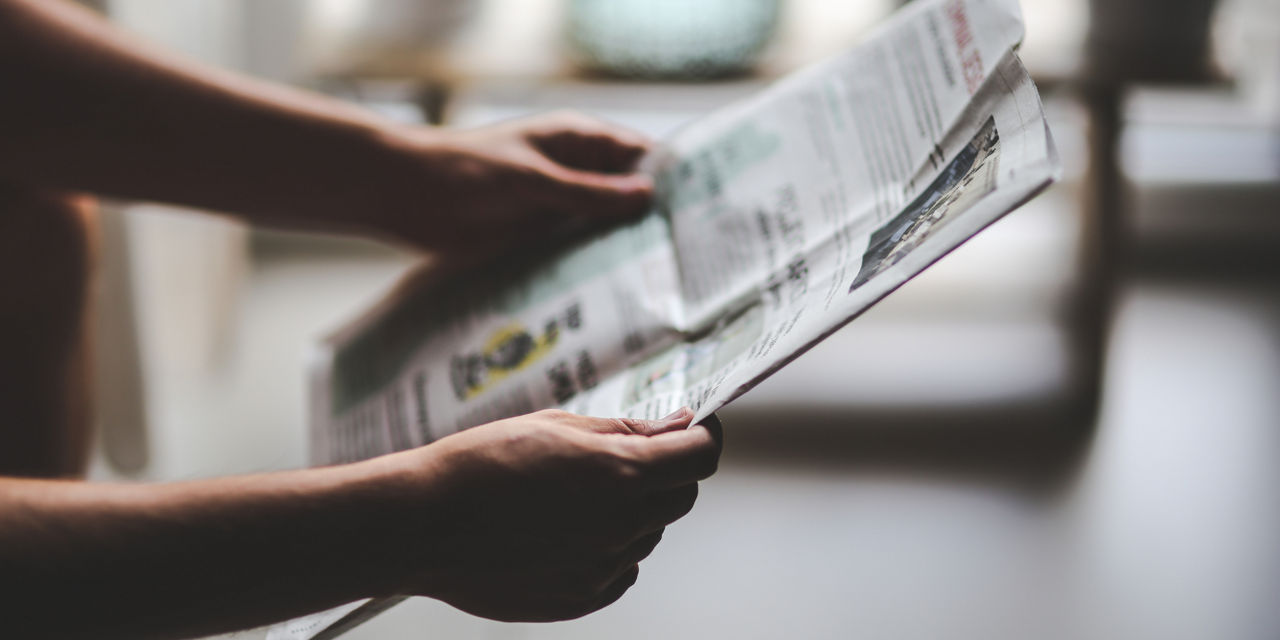 Eine Person hält eine Zeitung.