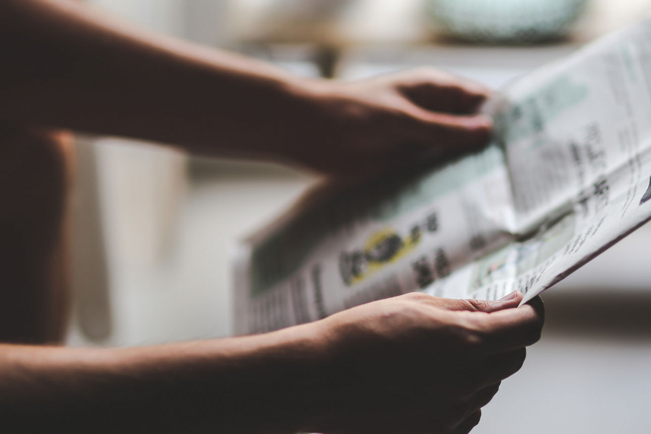 Eine Person hält eine Zeitung.