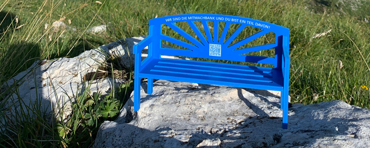 Kleine blaue Bank steht auf einem Stein an einer Wiese