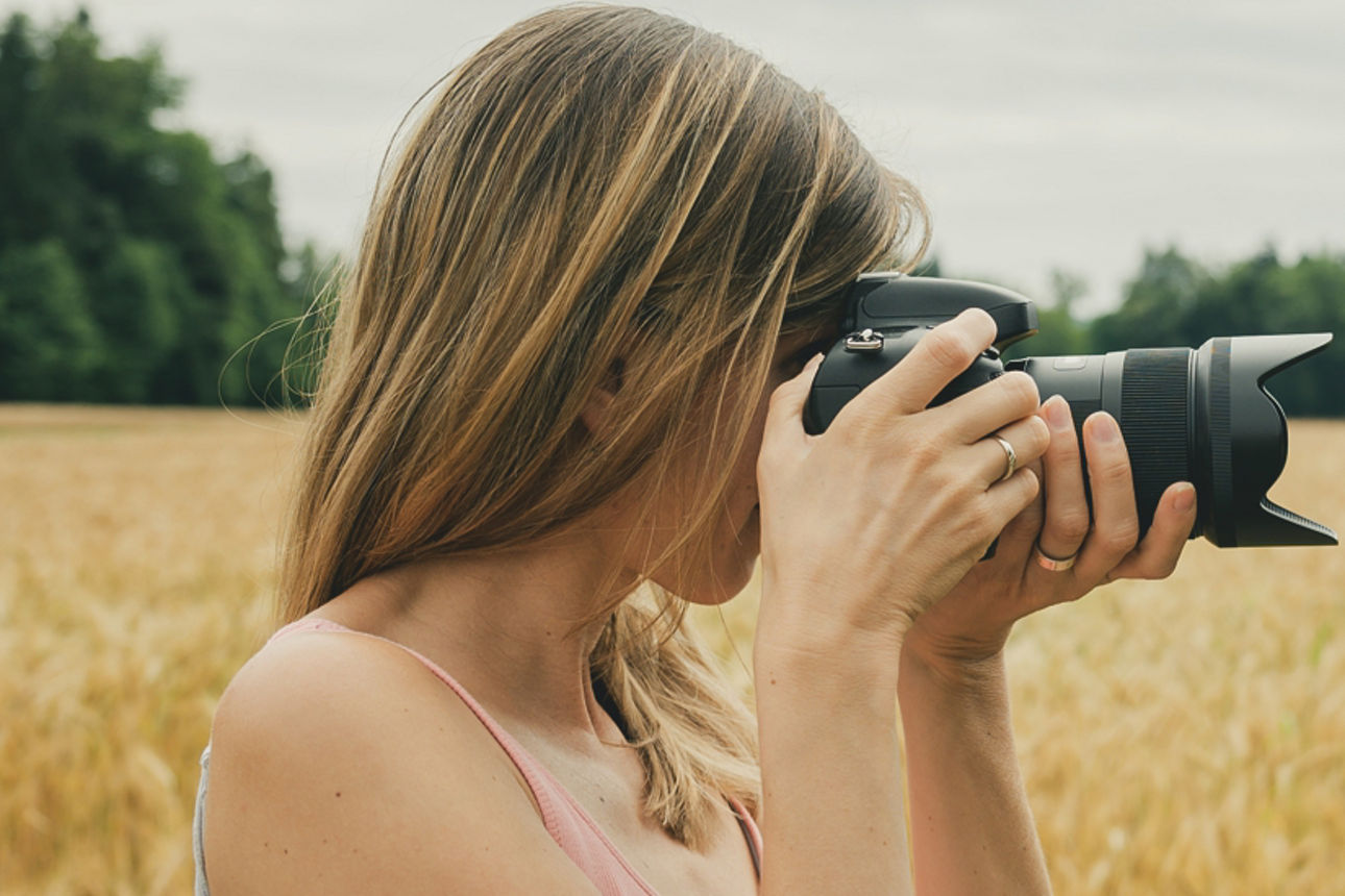 Junge Frau hat Kamera in der Hand und fotografiert eine Landschaft