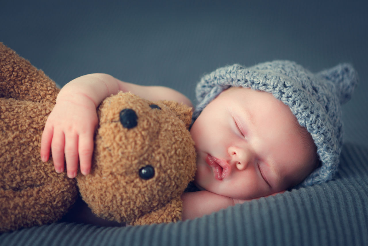 Schlafendes Baby mit Teddy im Arm