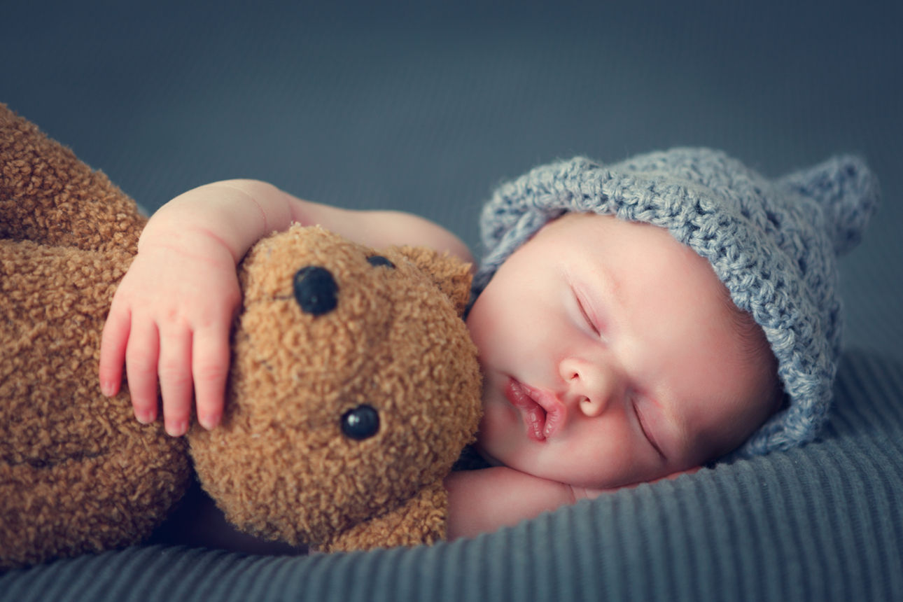 Schlafendes Baby mit Teddy im Arm