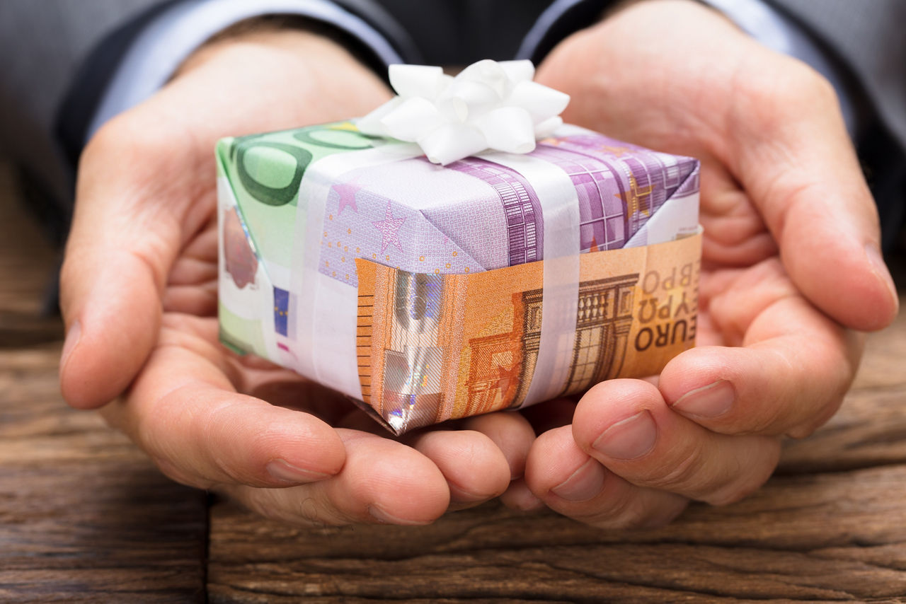 Mensch hält kleines Geschenk-Päckchen in den Händen
