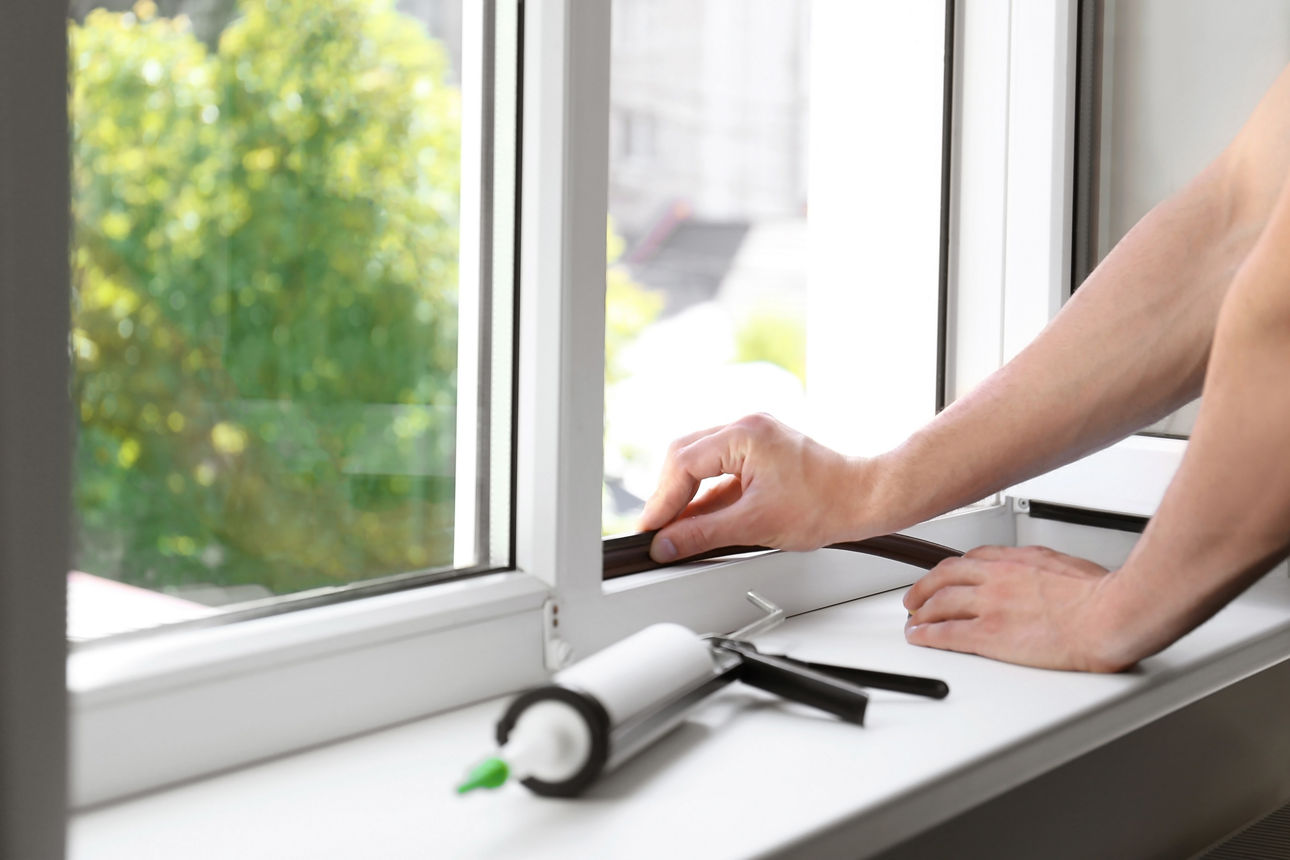 Bauarbeiter tauscht am Fenster die Isolierung von innen aus.
