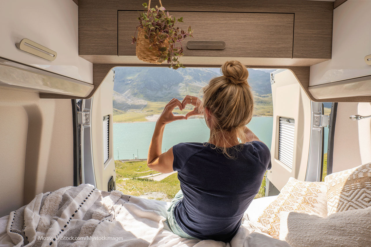 Frau im Camper zeigt mit ihren Fingern ein Herz