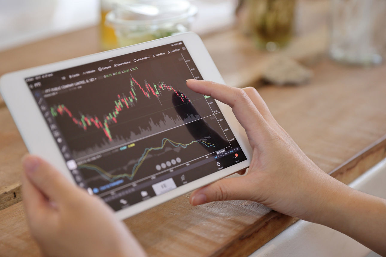 Frauenhand, die in einem Café ein Tablet zum Online‑Aktienhandel verwendet, Geschäftskonzept.