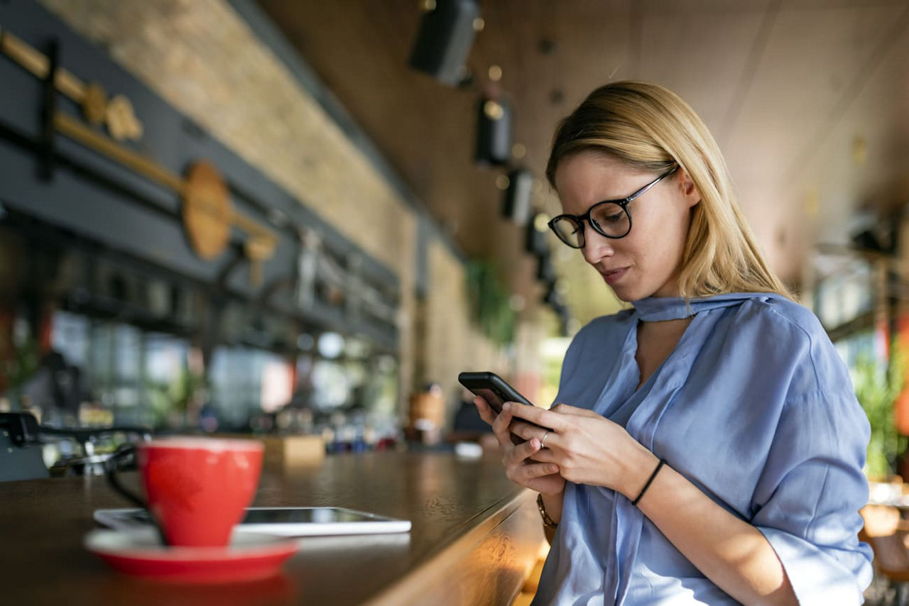 Eine junge Unternehmerin überprüft in einem Café ihr Smartphone