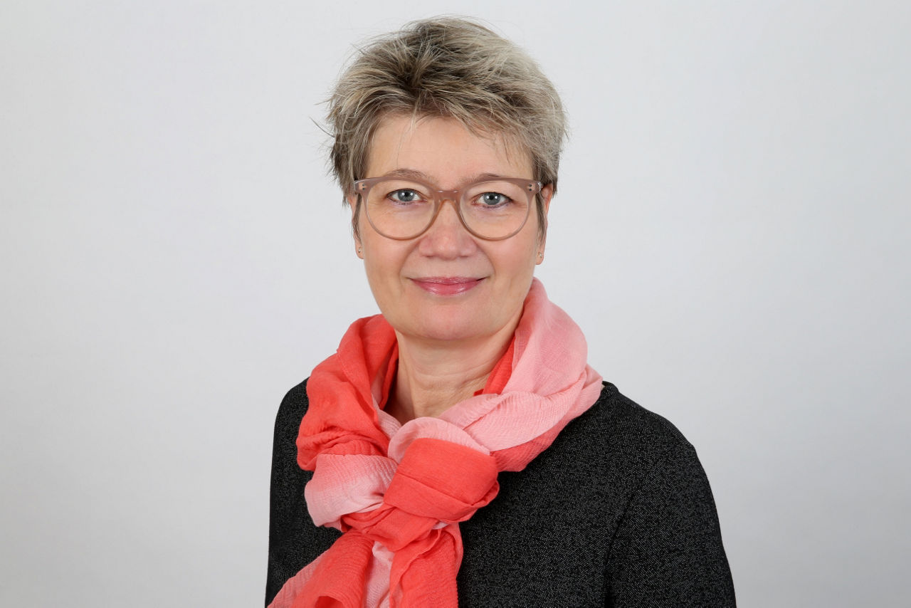 Eine lächelnder Frau schaut in die Kamera.