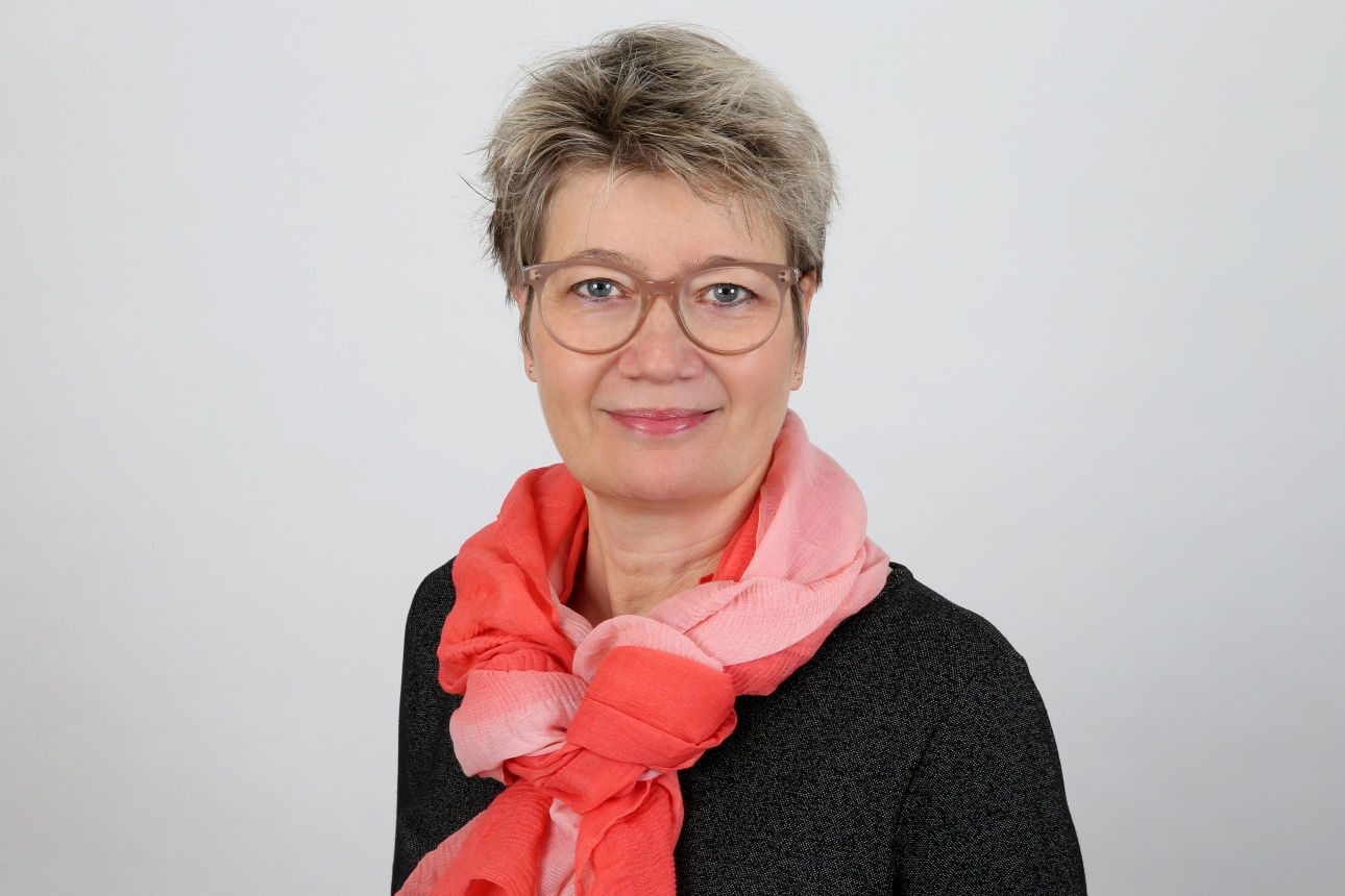 Eine lächelnde Frau schaut in die Kamera.