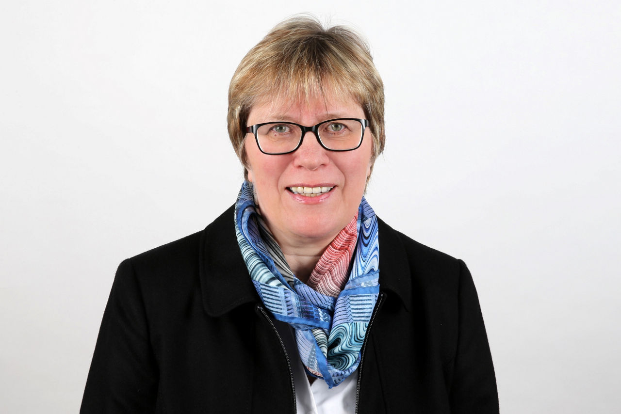 Ein lächelnder Frau schaut in die Kamera.