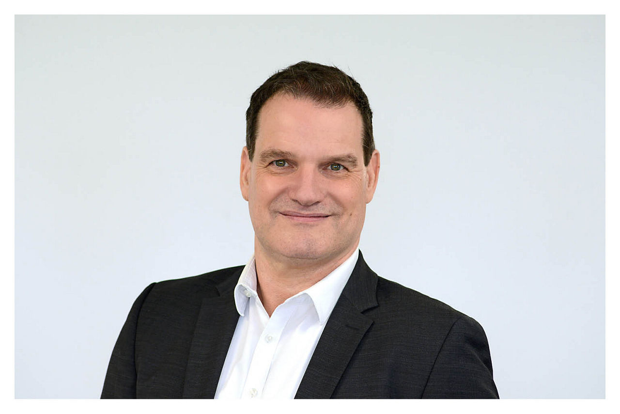 Firmenkundenberater Andreas Brüser vor grauen Hintergrund