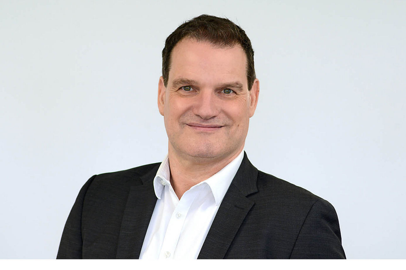 Firmenkundenberater Andreas Brüser vor grauen Hintergrund