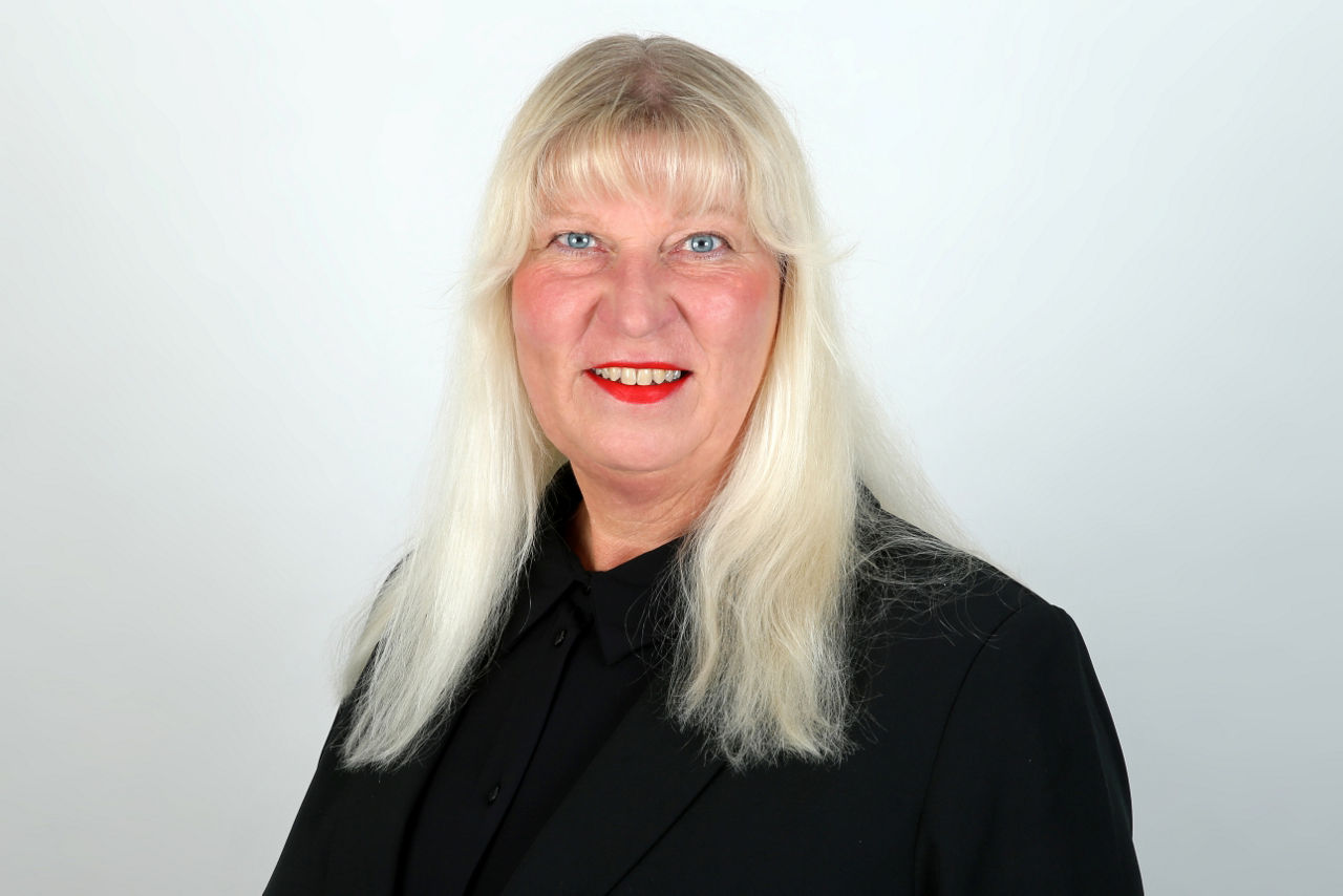 Eine lächelnder Frau schaut in die Kamera.