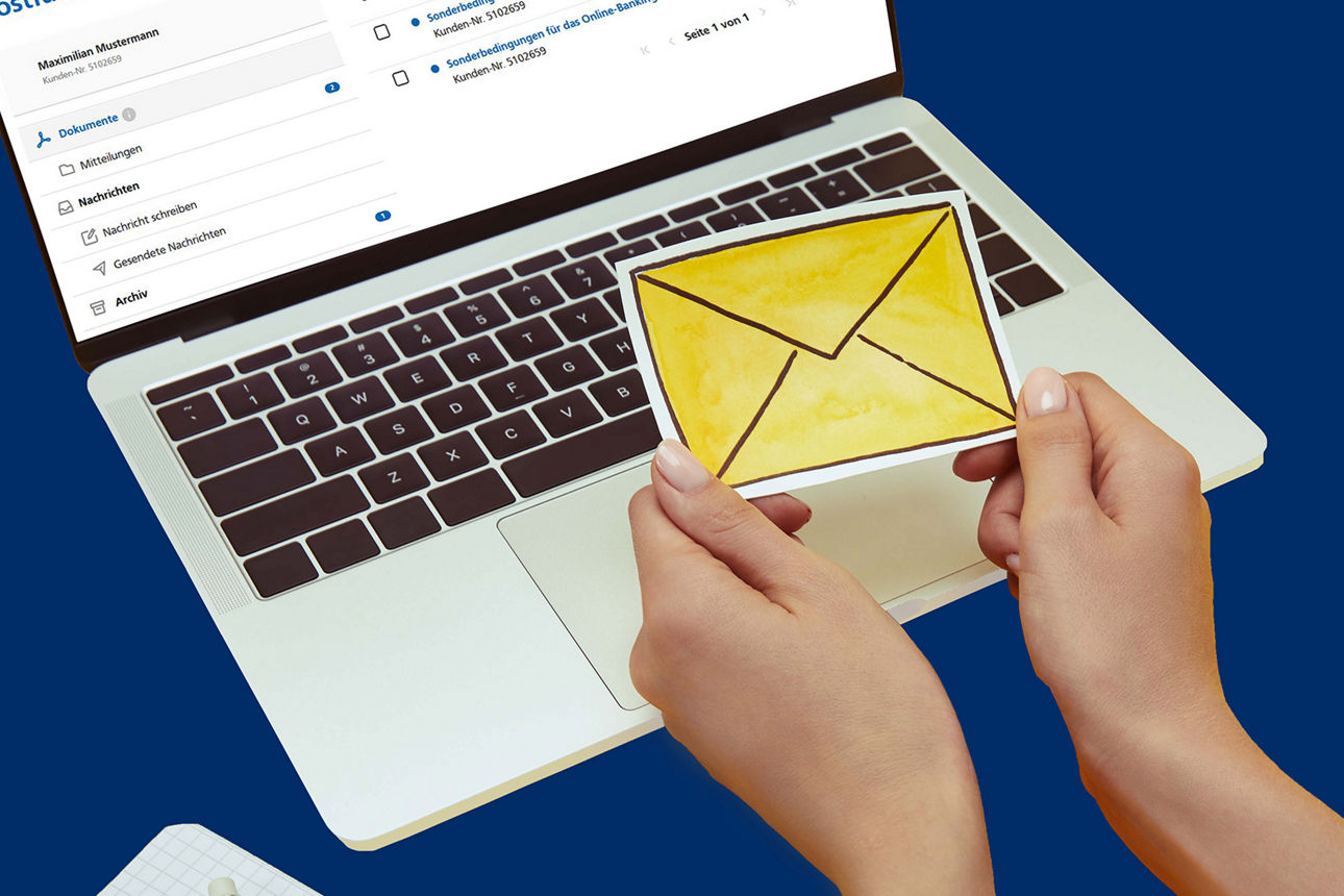 Laptop und zwei Hände die ein Bild mit einem gelben Briefumschlag umfassen
