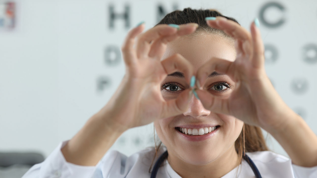 junge Frau beim Optiker formt Brille mit den Händen