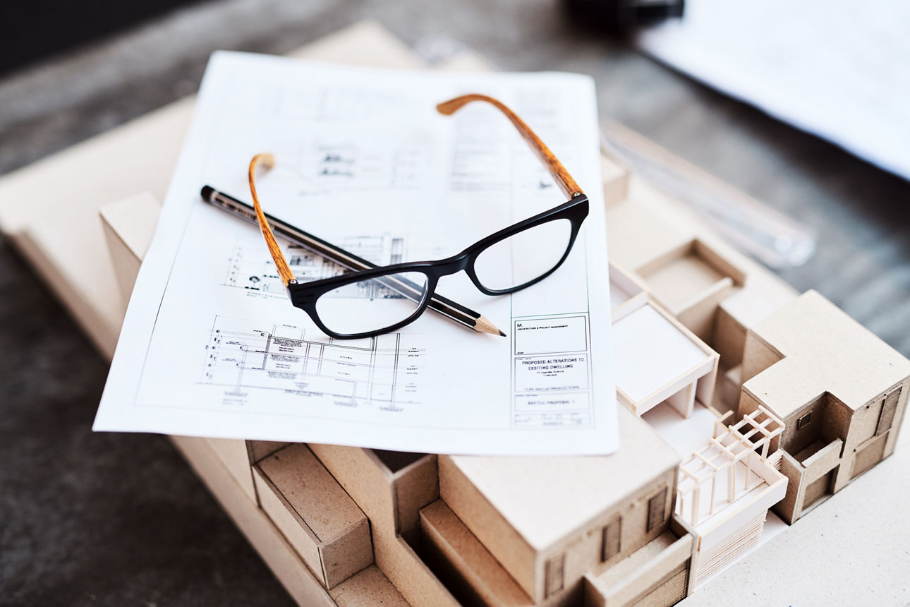 Plan mit Brille und Modell eines Hauses